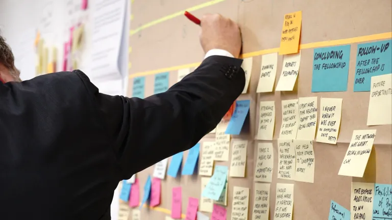 man writing on a wall of sticky notes